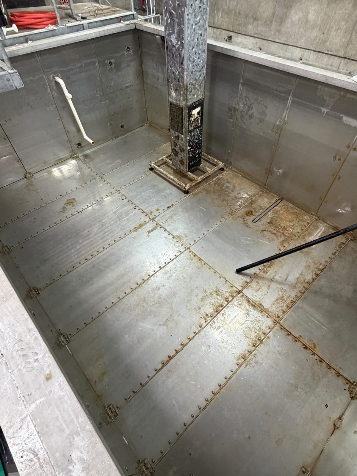 Bolted steel floor panels and central support column inside an open tank