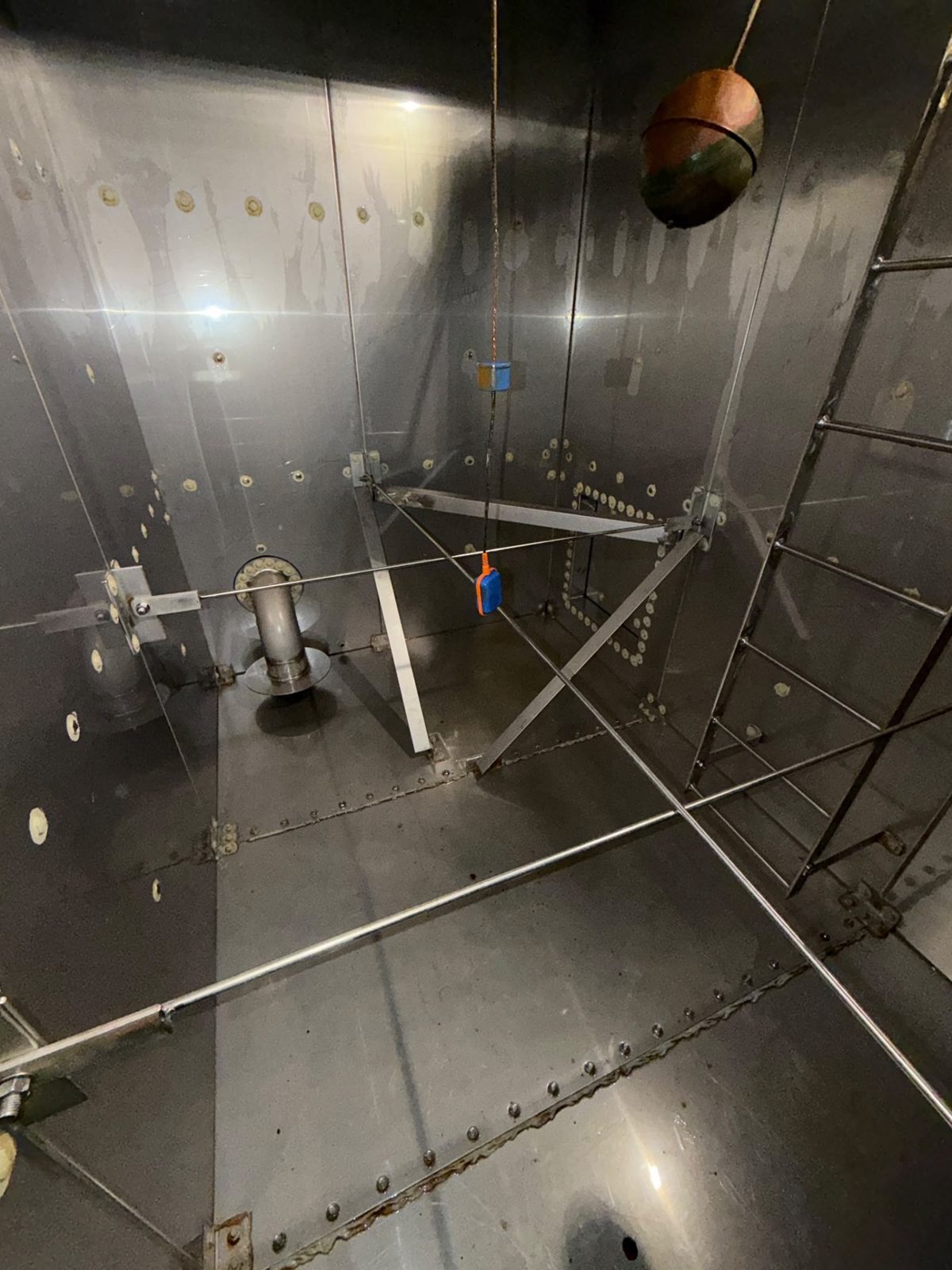 Interior of a steel panel tank showing internal bracing, tie rods and a float valve
